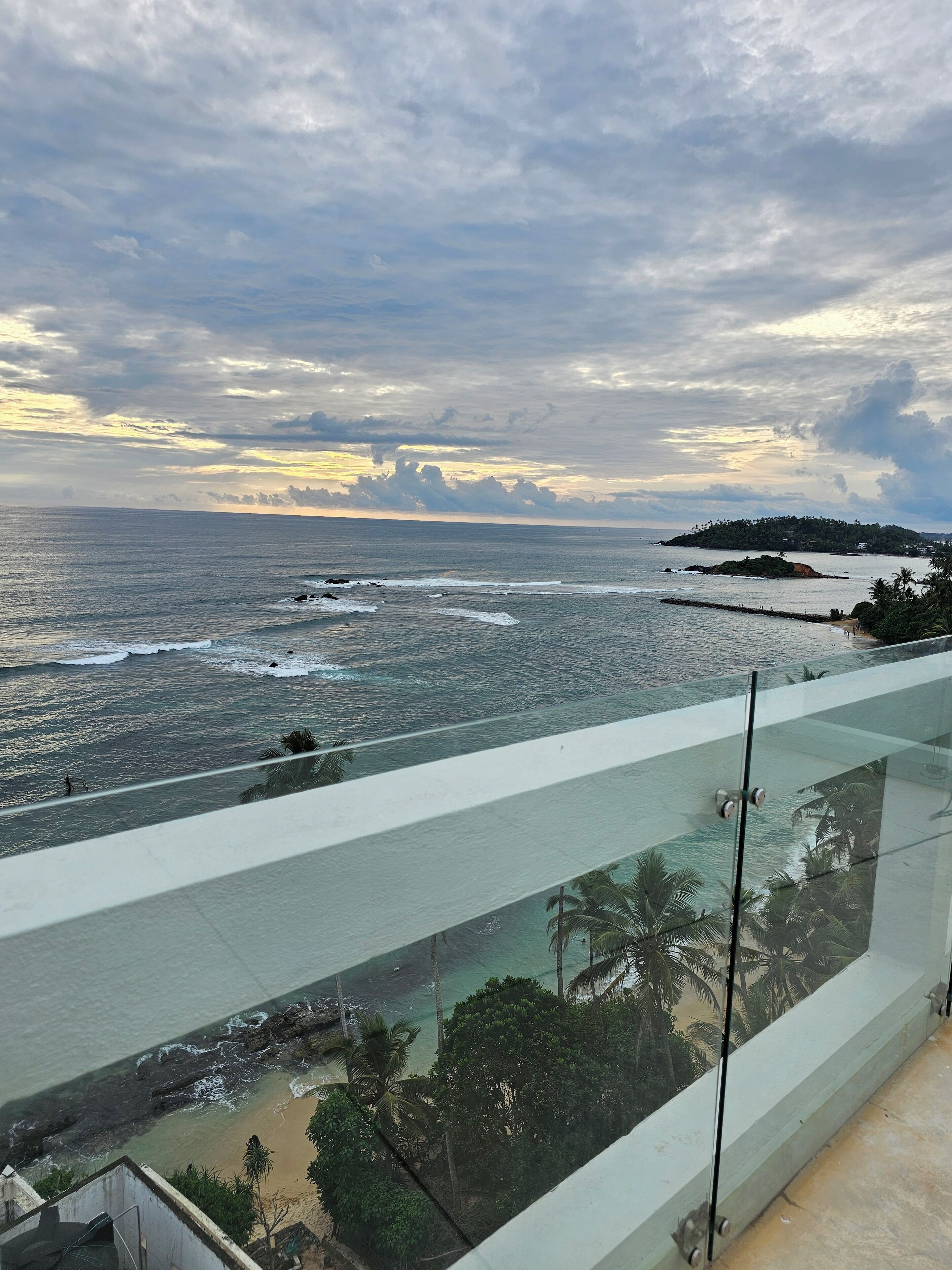 A balcony with a view of the ocean and a distant island.