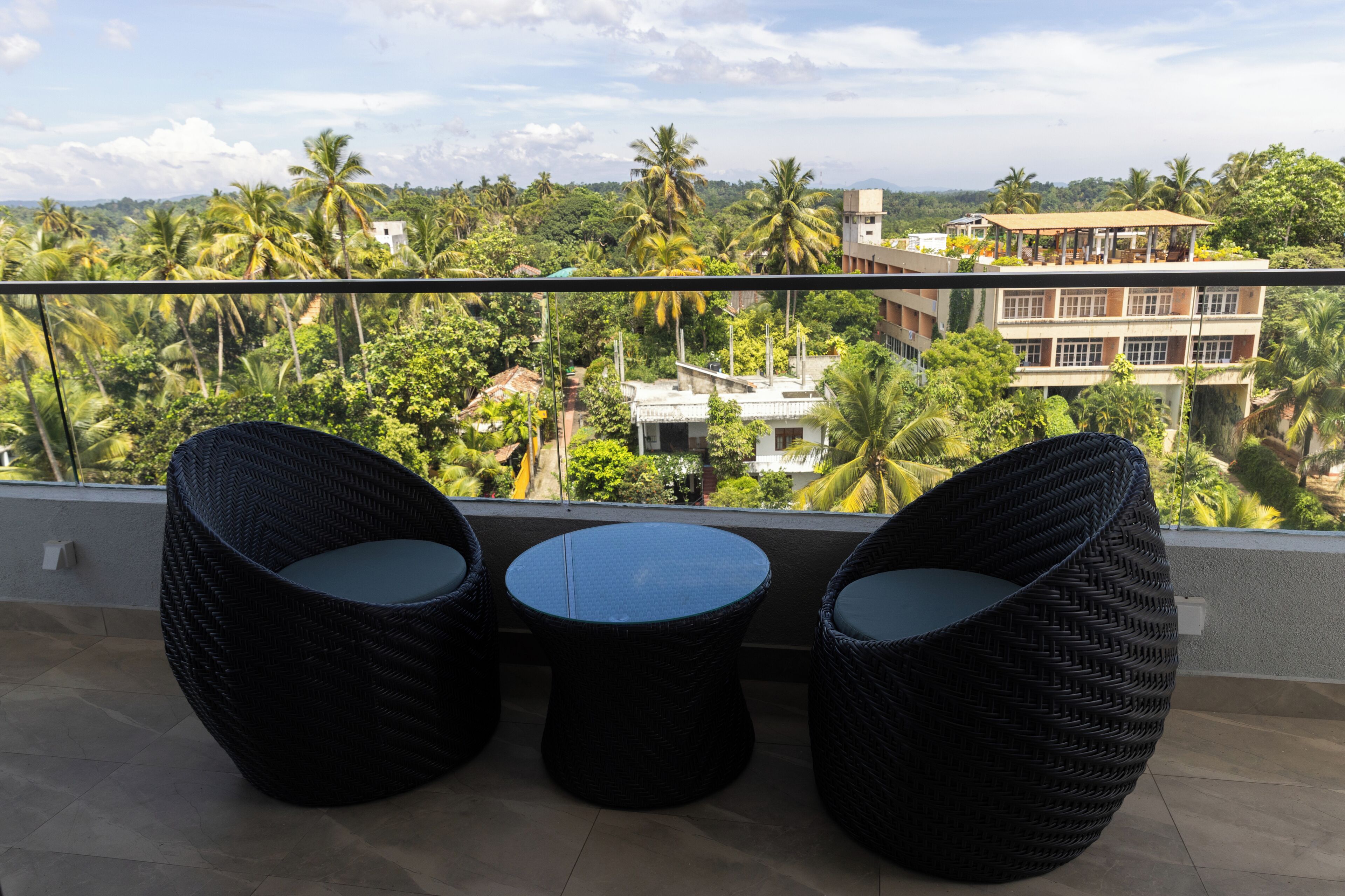 Varanda com mobiliário de vime e vista para uma paisagem tropical.