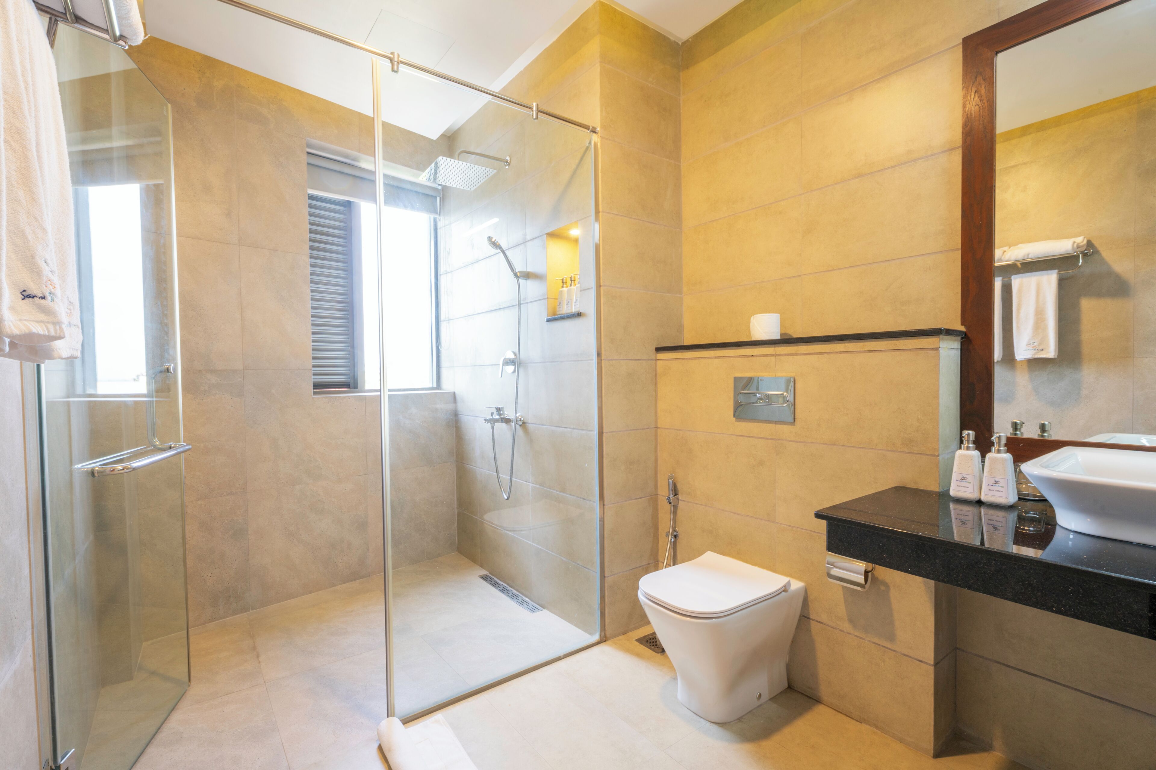 Ein modernes Badezimmer mit Duschkabine aus Glas, einer weißen Toilette und einem schwarzen Waschtisch mit Spüle und Toilettenartikeln.