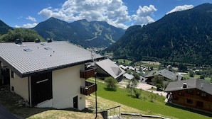 Un village de montagne aux maisons traditionnelles, sous un ciel dégagé, surplombant une vallée.