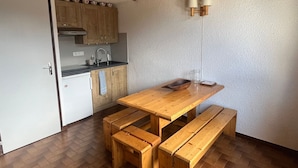 Une cuisine compacte avec des meubles de rangement en bois, un évier et une table à manger en bois, accompagnée de bancs.