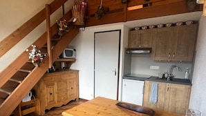 Une cuisine compacte avec des meubles en bois, un four à micro-ondes encastré et un évier.