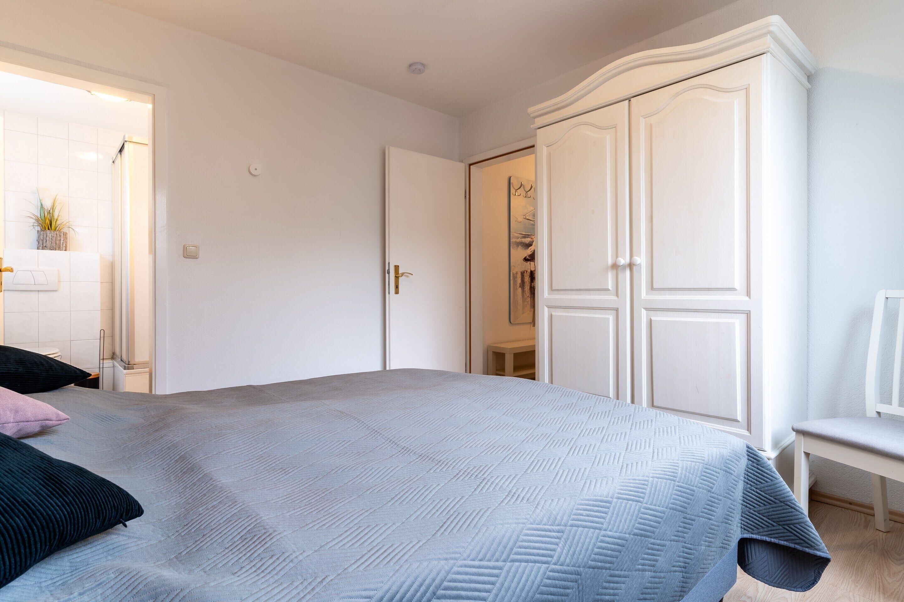 Een slaapkamer met een bed, een kledingkast en een bankje.