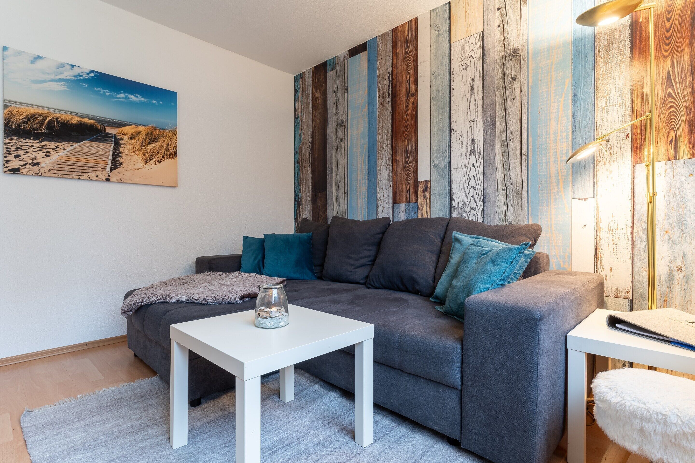 Un salon moderne avec un canapé gris, une table basse blanche et un mur en bois rustique.