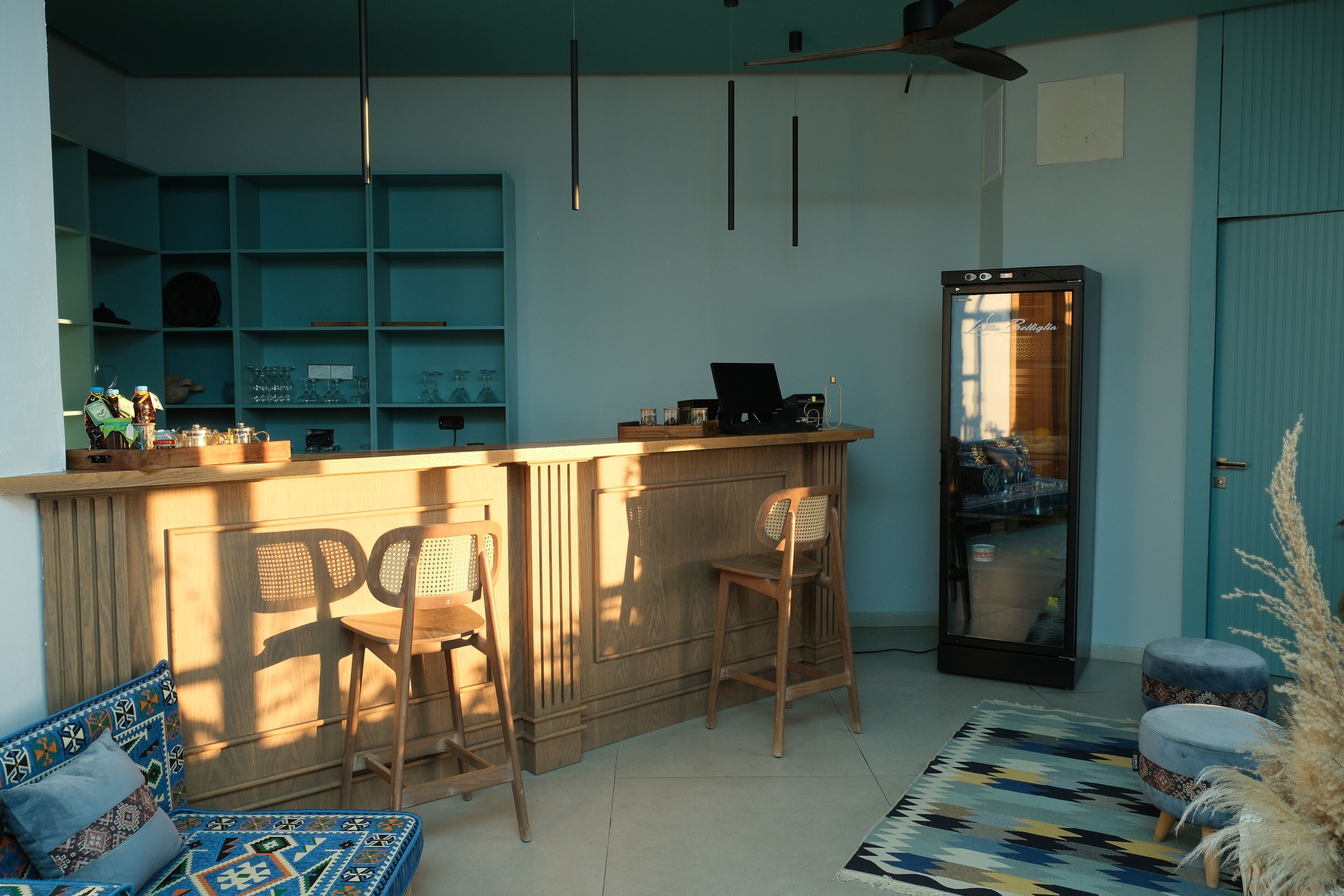 Una habitación acogedora con una barra de madera, dos sillas de madera, un tapete estampado y una puerta azul.