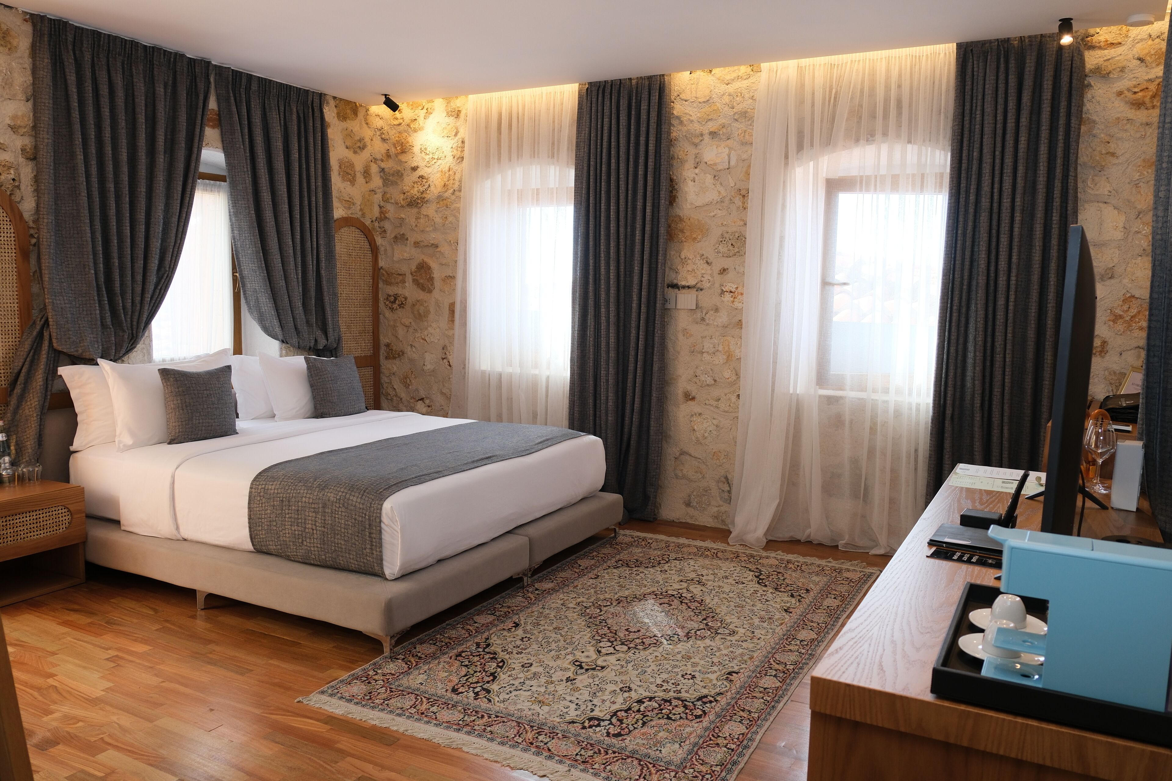 Une chambre moderne avec un grand lit, un bureau avec un ordinateur et un mur en pierre.