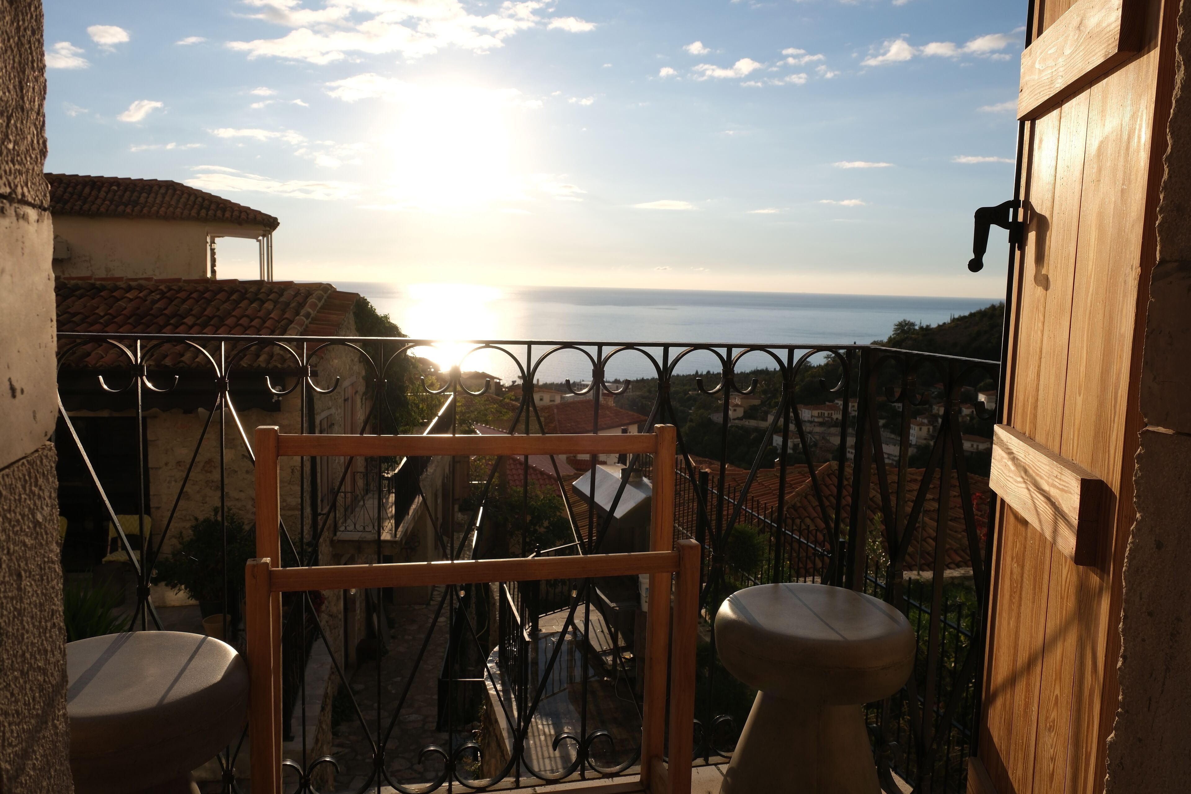 Un balcón con vista al mar, una puerta de madera y una barandilla de metal.