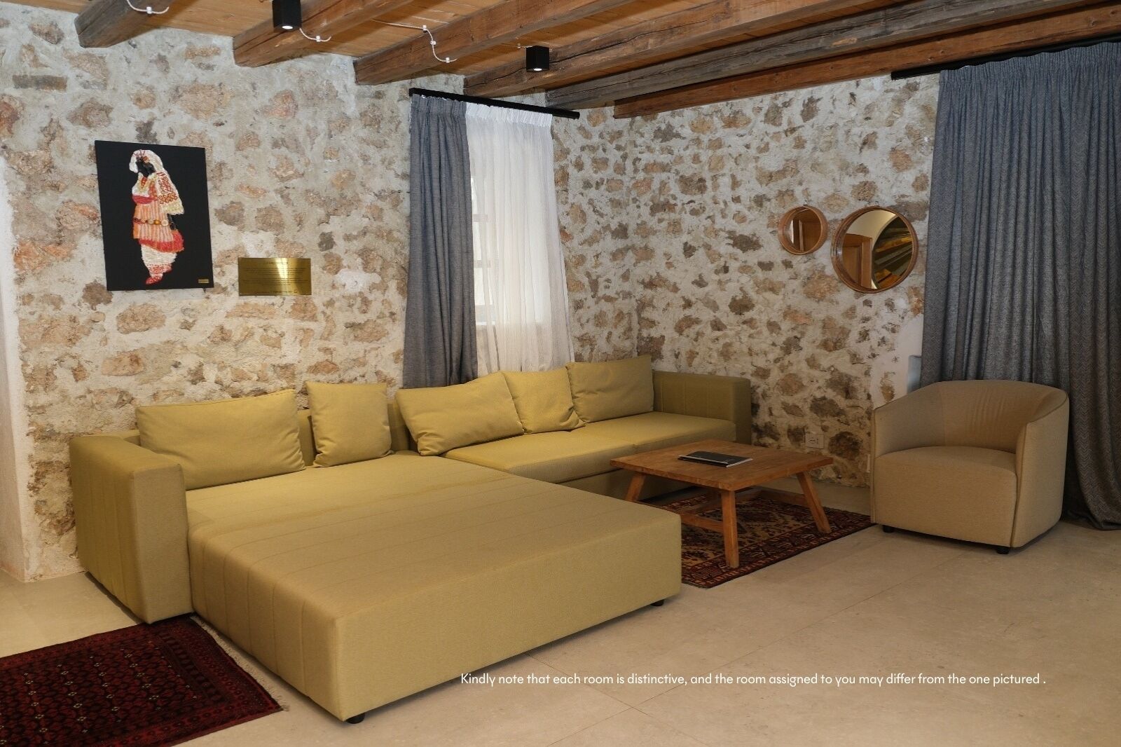 Uma sala de estar com sofá, mesa de centro de madeira, cadeira, quadro e parede de pedra.