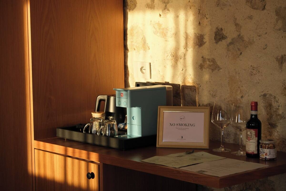 A bar area with a coffee machine, wine glasses, and a bottle of wine. A 'No Smoking' sign is visible.