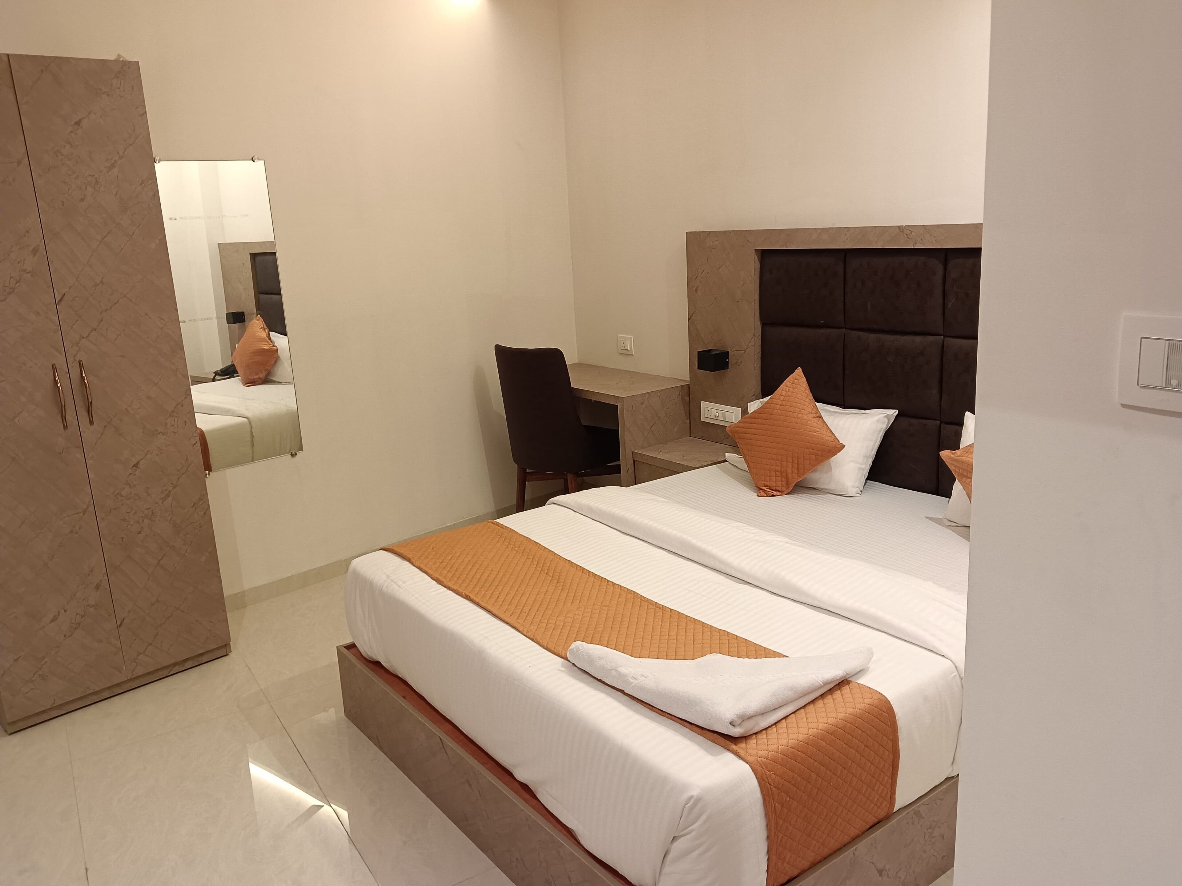 A hotel room with a large bed, a desk, and a wardrobe.