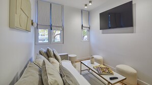 Una sala de estar moderna con un sofá, una mesa de centro y un televisor de pantalla plana montado en la pared.