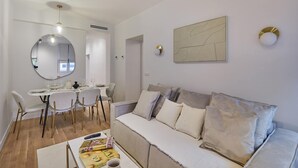 A modern living room with a dining area, a sofa, and a round mirror. - Superb Apartment in the Heart of Paris (Paris)