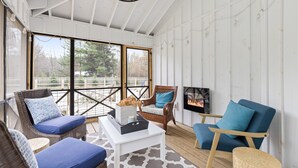 A sunlit room with wicker furniture, a white coffee table, and a TV on the wall. - Remodeled, Private Pool & Hot Tub, Beach Nearby (Union Pier)