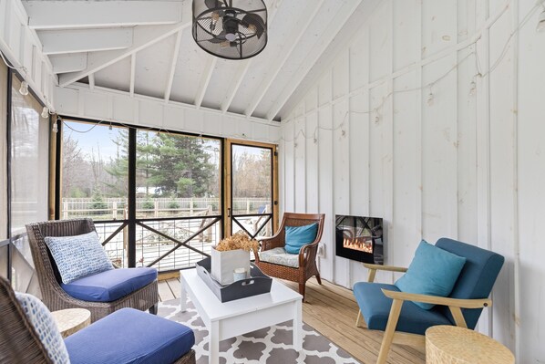 A sunlit room with wicker furniture, a white coffee table, and a TV on the wall.
