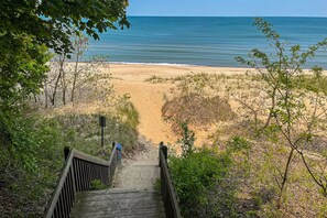 A wooden staircase leading to a beach with a clear view of the ocean.