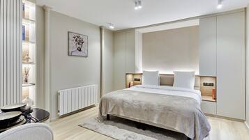 Un dormitorio moderno con una cama grande, mesitas de noche, un radiador y una estantería en la pared.