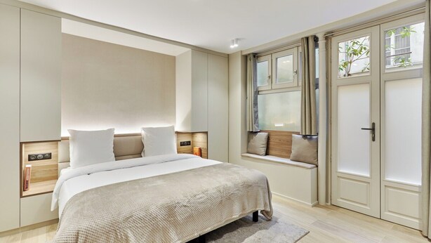 A bedroom with a large bed, built-in nightstands, a window seat, and a wardrobe. - Sublime and new Studio Center of Paris (Paris)