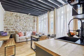 Ein gemütliches Wohnzimmer mit Steinwand, Holzboden und Essbereich mit Tisch und Stühlen.