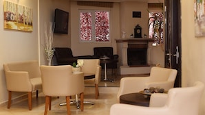 Un salon avec des canapés de couleur beige, une cheminée et un téléviseur fixé au mur.