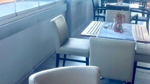Un restaurant offrant une vue sur le front de mer, avec une terrasse et une salle à manger fermée par des baies vitrées.