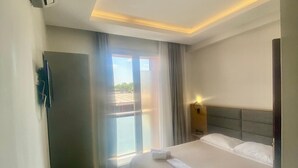 Une chambre d’hôtel avec un lit, une chaise, un bureau et une fenêtre avec des rideaux.