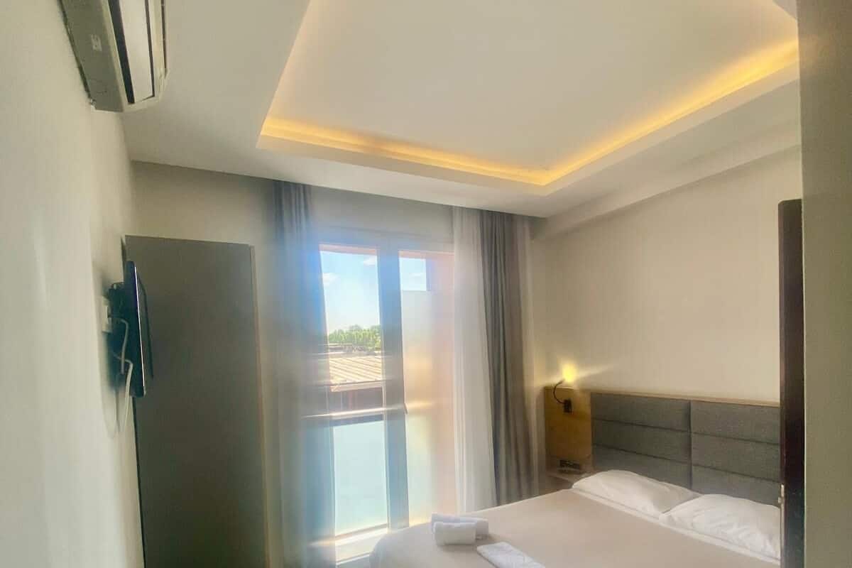Una habitación de hotel con cama, una silla, un escritorio y una ventana con cortinas.