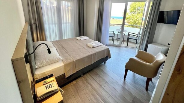 Une chambre d’hôtel comprenant un lit, un bureau avec un téléphone, une chaise et un balcon avec vue sur la mer.
