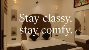 A modern bedroom with a bed, bedside tables, a ceiling fan, and a large mirror. - Hotel Mango Tree (Hansi)