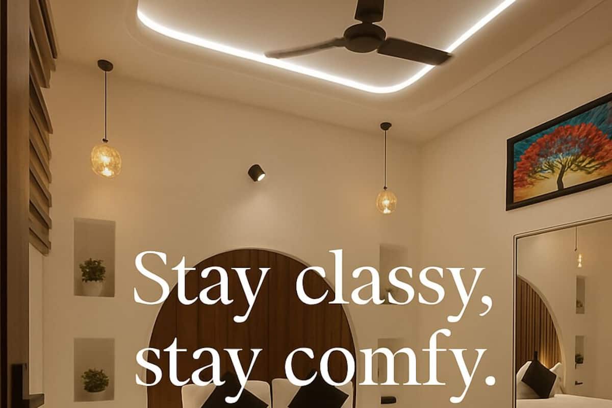 Egy modern hálószoba, amelyben található egy ágy, éjjeliszekrények, egy mennyezeti ventilátor és egy nagy tükör.