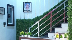 A reception desk with a sign that reads "RECEPTION" in a modern building with a staircase and greenery. - Hotel Mango Tree (Hansi)