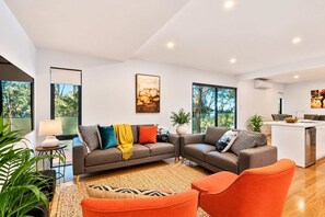 A modern living room with a sofa, a coffee table, and a kitchen area with a dining table.