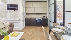 Una cocina moderna con armarios oscuros, horno empotrado y televisor de pantalla plana montado en la pared.