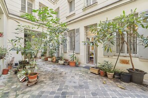 A courtyard with potted plants and a tiled floor. - Superb Apartment Louvre Saint Honorer (Paris)