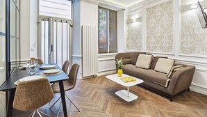 Una sala de estar moderna con un sofá marrón, una mesa de centro blanca y un comedor con una mesa azul y sillas marrones.