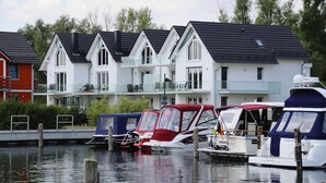 Eine Reihe moderner Häuser mit angestücktem Boot davor.