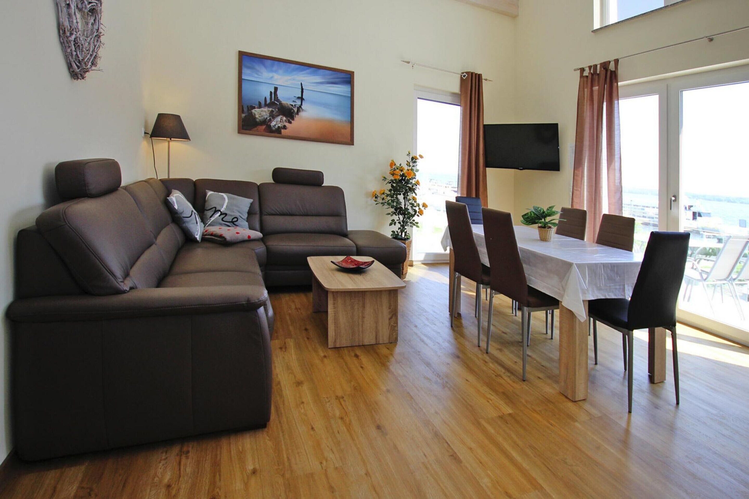 A modern living room with a sofa, a coffee table, and a dining area with chairs and a table.