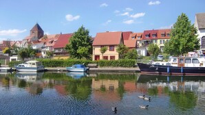 Ein ruhiger Fluss mit Booten und Enten, umgeben von traditionellen Häusern mit roten Dächern.