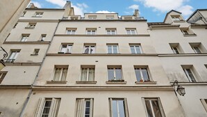 Un edificio a più piani con architettura classica, caratterizzato da finestre e persiane regolarmente distanziate.
