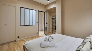 Una camera da letto con un letto, un armadio, una porta che dà su un bagno e uno scaffale con asciugamani.