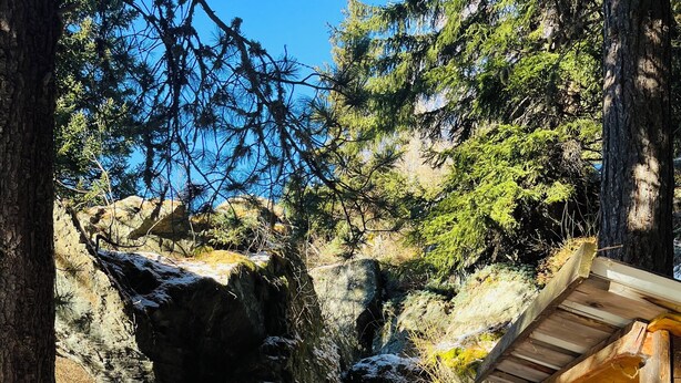 Eine rustikale Holzhütte, umgeben von verschneiter Landschaft und felsigem Gelände.