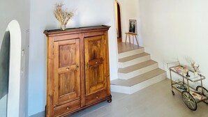Ein Holzkabinent mit Schubladen, ein kleiner Tisch mit einer Vase und eine Treppe, die in einen anderen Raum führt.