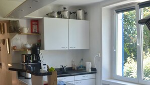Una cocina moderna con armarios blancos, encimera negra y ventana con vistas a zonas verdes.