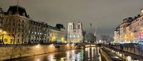 A nighttime view of a river with buildings on either side, a bridge, and a prominent cathedral in the background.