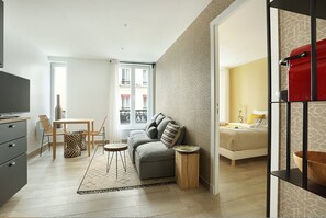 Un appartamento moderno con soggiorno, zona pranzo e camera da letto. Dispone di un divano, un tavolo da pranzo, sedie, una TV e un letto.