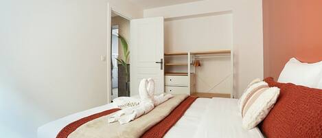 A hotel room with a bed, a wardrobe, and a door leading to a bathroom.