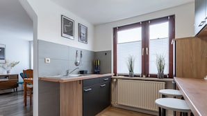 A modern kitchen with a wooden island, black cabinets, and a window with blinds. - Ferienwohnung in Busum (Büsum)