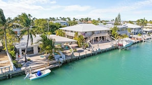 Uma propriedade costeira com um cais, um barco e uma casa grande com varanda com vista para a água.