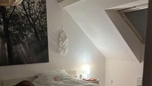 A bedroom with a bed, a nightstand, a lamp, and a dreamcatcher. - Vacation apartment  (Vettweiß)