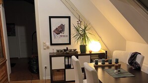 A dining area with a wooden table and chairs, a potted plant, and a framed picture on the wall. - Vacation apartment  (Vettweiß)