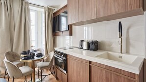 Une cuisine compacte avec des meubles en bois, un four encastré, un évier et un téléviseur à écran plat fixé au-dessus du plan de travail.